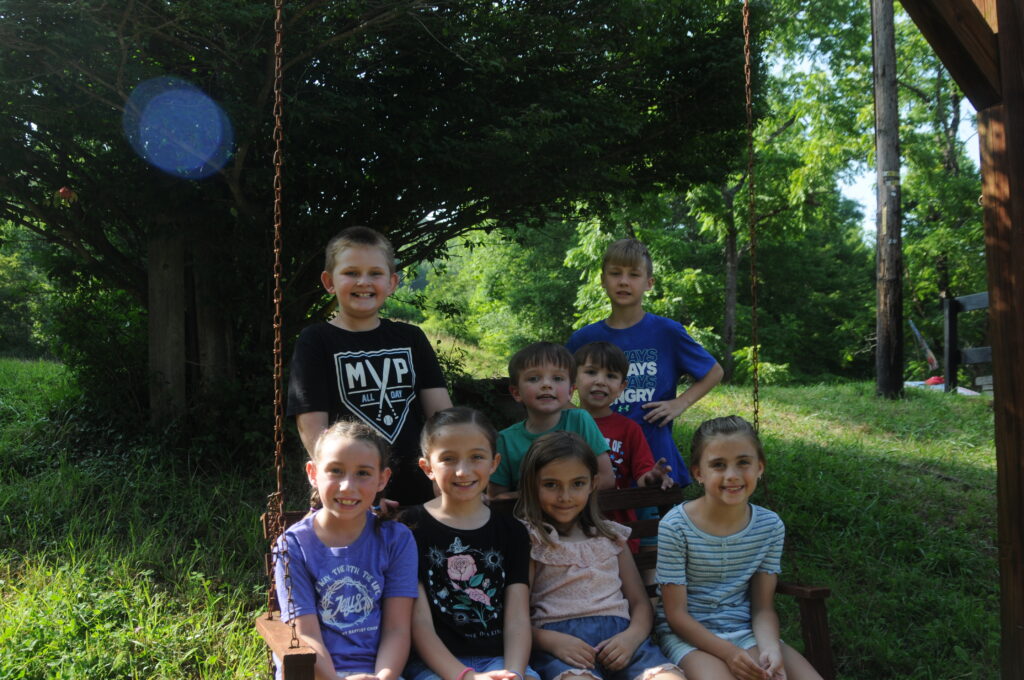 A group of children on a swing in the woods.