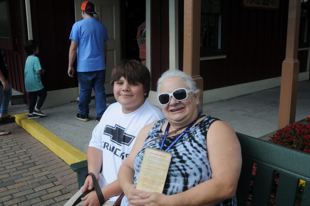 A kin caregiver and child smile for the camera as they sit together on a bench.