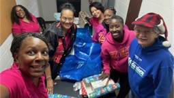 Volunteers pose for a photo as they participate in a Christmas gift wrap party