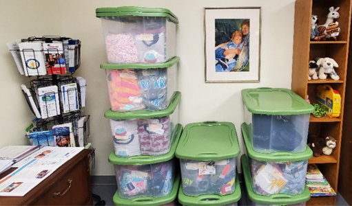 A photograph of the resource room at KKNC, which contains written resources like leaflets, brochures, and booklets, as well as tubs of clothes, stuffed animals, and other supplies