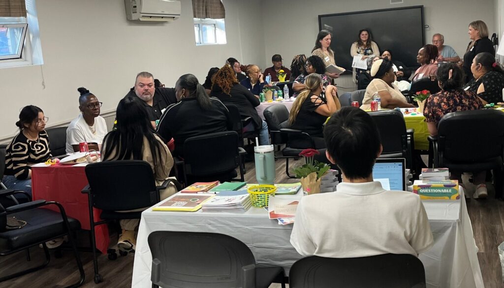 Photograph of a Parent Café session for kin caregivers, with a diverse group of adults sitting at multiple tables in a meeting room