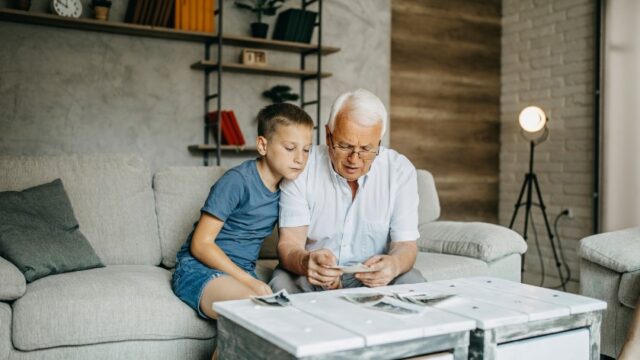 A white grandfather and grandson look at old family photos together.