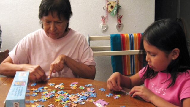 A Native grandmother and her granddaughter work on a puzzle together