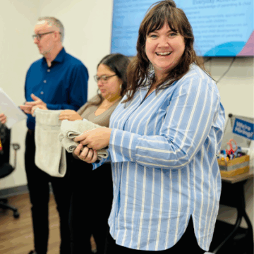 Woman smiling and facing the camera while holding hand towels and standing next to two people