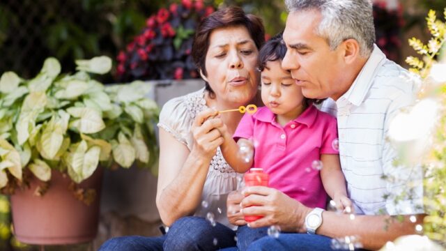 grandchild blowing bubbles with grandparents