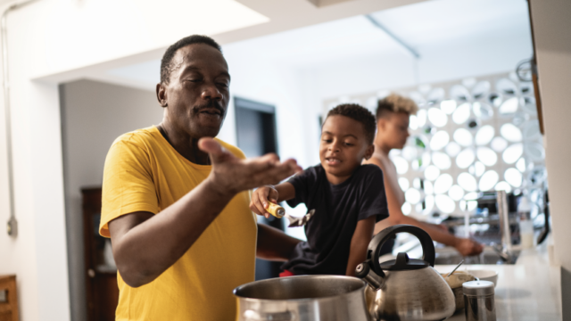 A Black grandfather and young grandson are cooking together at home.
