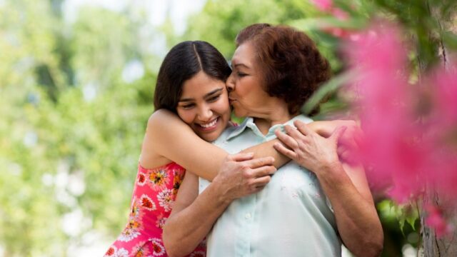 A Latina grandmother and teenage granddaughter embrace