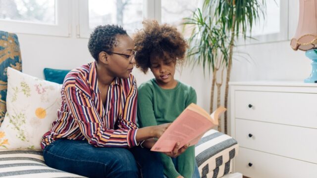 A Black grandmother reads a chapter book with her grandchild